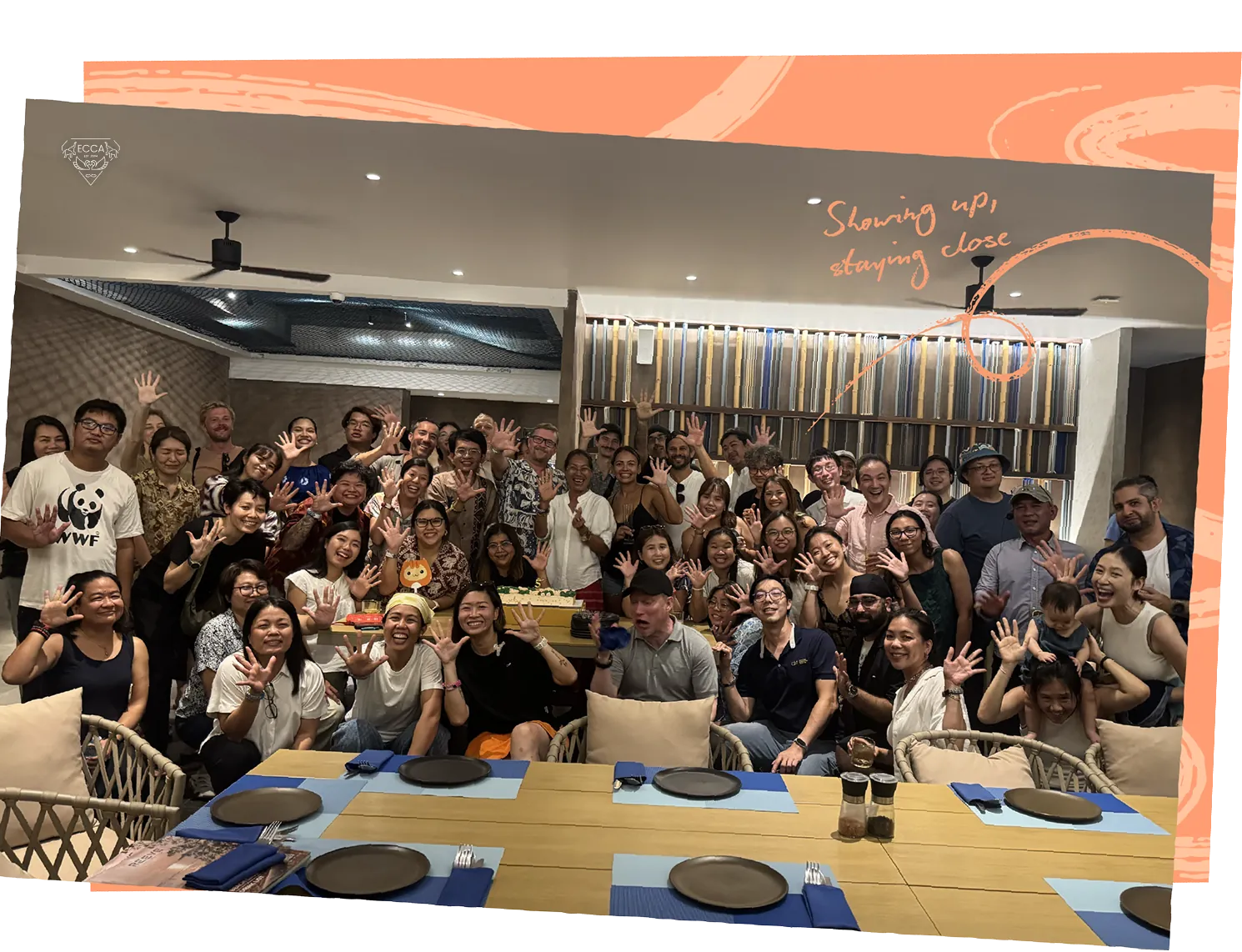 ECCA partners and staff crowded around a long table, smiling and waving at the camera. Handwritten caption: Showing up, staying close.