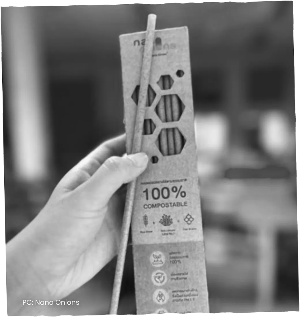 A hand holding a paper sleeve of straws labelled 100% compostable.