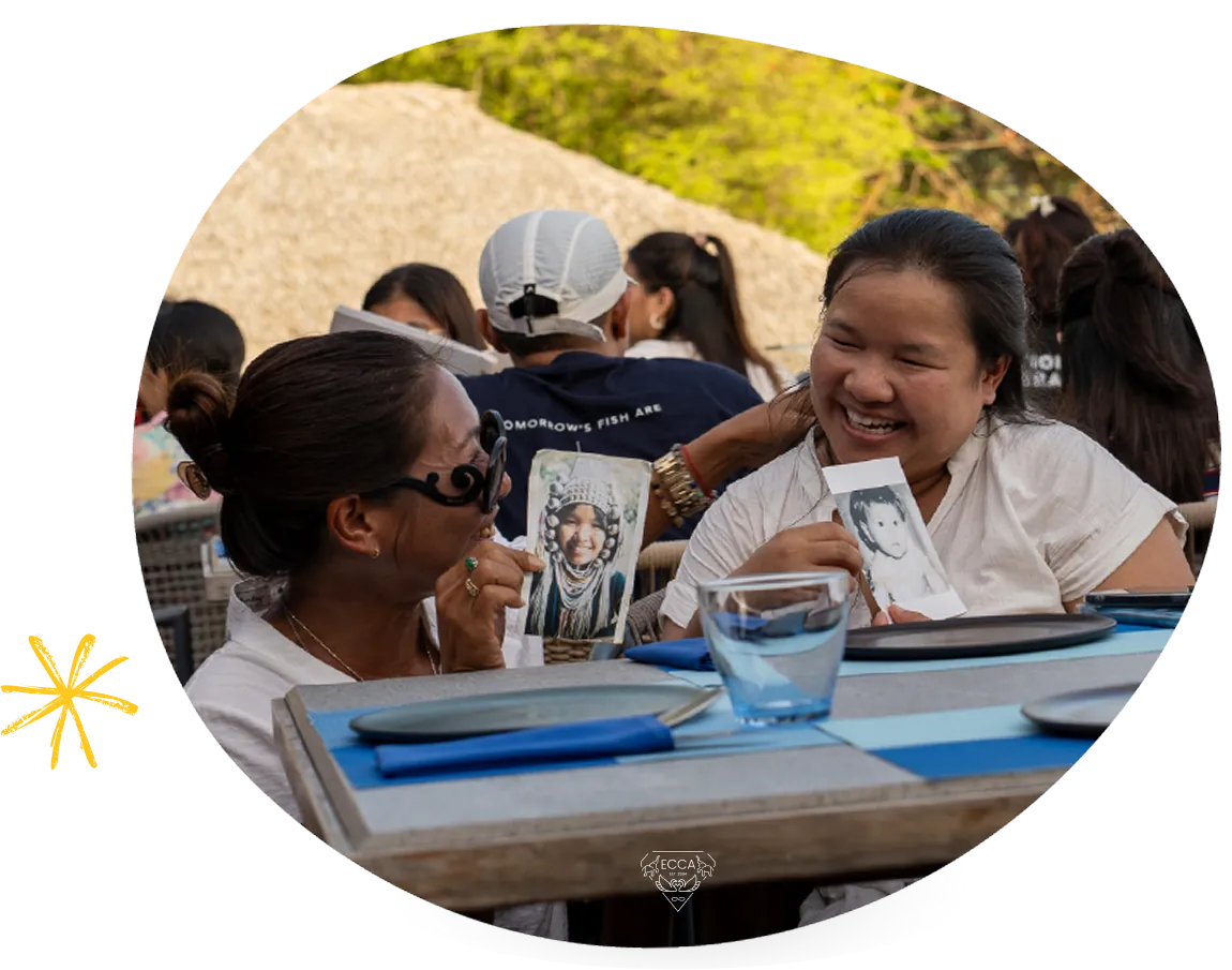 Two participants laughing together at a table, holding instant photographs.