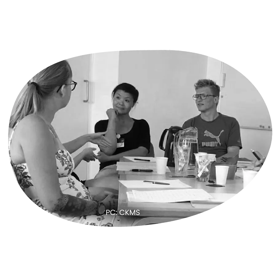 Three people in conversation around a table at a workshop.