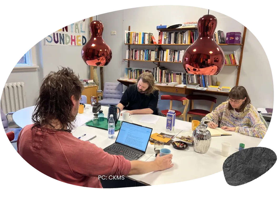 People working around a table in a room lined with bookshelves.