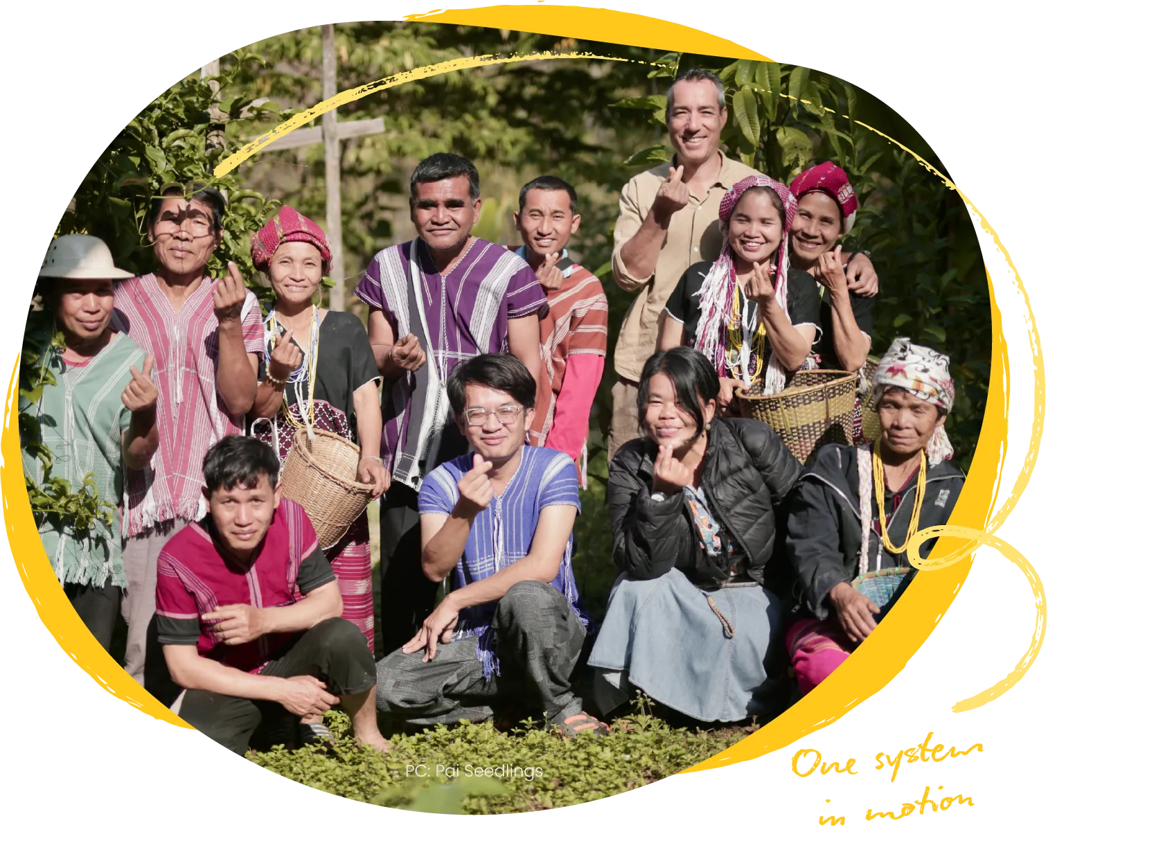 A large group of people in traditional dress standing and crouching together outdoors, several holding drums.