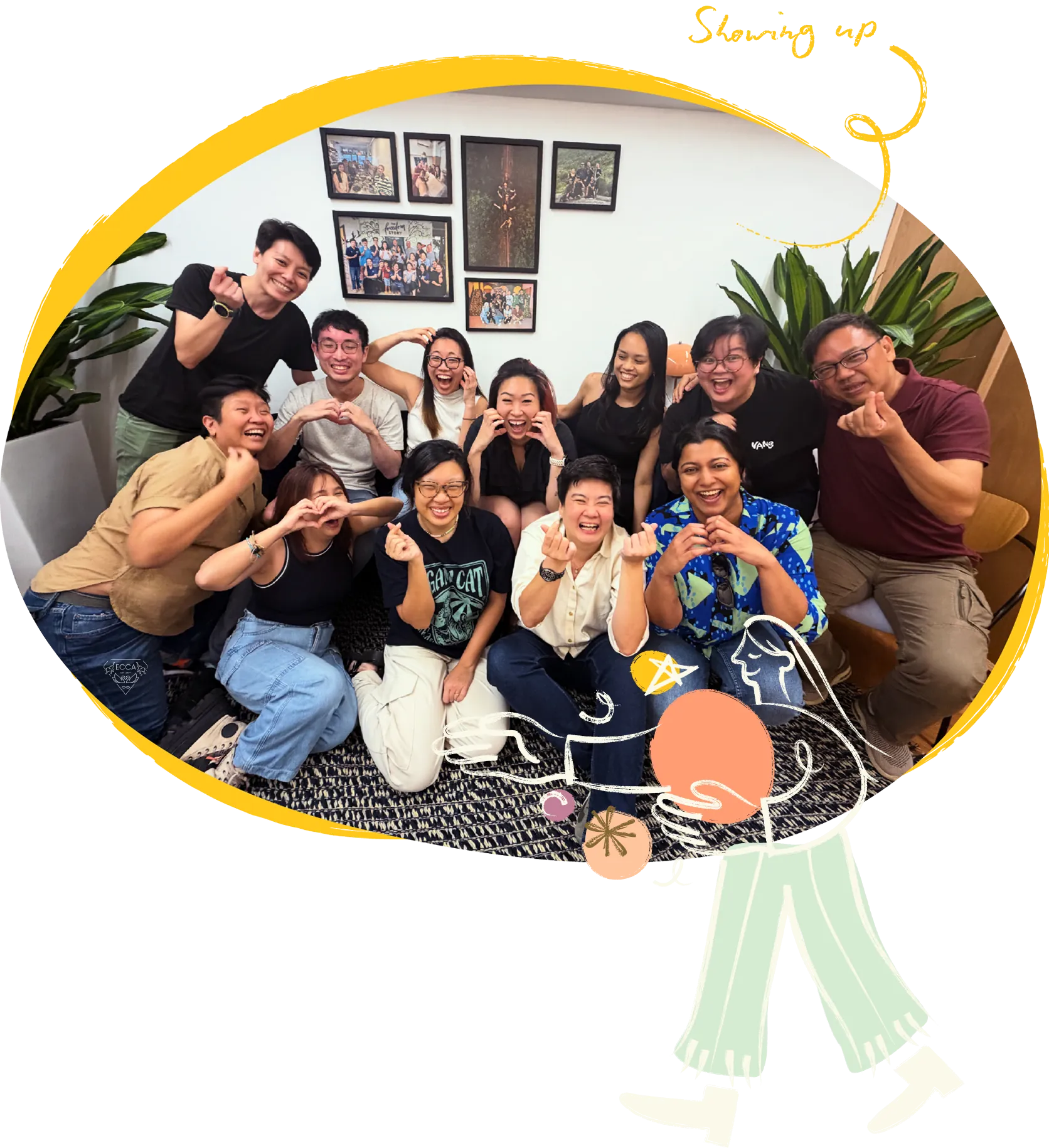 A group of people posing together and laughing in a room hung with framed photographs.